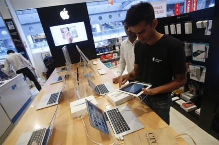 A salesperson unpacks an Apple iPad Mini to test it for a customer in the Apple specialty section of a Croma retail store in Mumbai February 22, 2013. REUTERS/Vivek Prakash